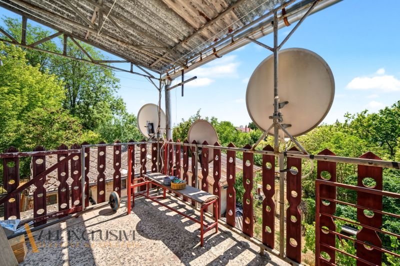 Der Balkon eines Einfamilienhauses in Bodza mit Satellitenschüsseln und Grün im Hintergrund.