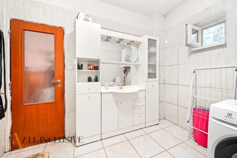 Badezimmer in einem Einfamilienhaus mit weißen Möbeln und einer Waschmaschine.