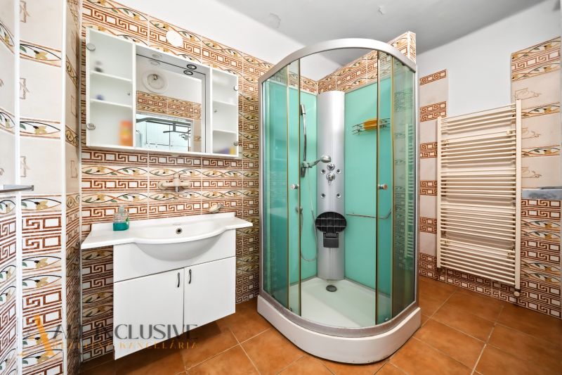 Badezimmer in einem Einfamilienhaus mit Duschkabine und Keramikfliesen.