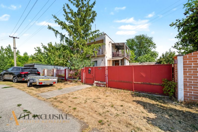 Ein Einfamilienhaus in Bodza mit Garten, Auto und Anhänger an der Straße.