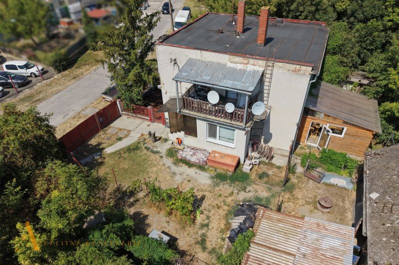 Ein Einfamilienhaus in Bodza mit zwei Schornsteinen, einer Terrasse und einem weitläufigen Garten mit Bäumen.