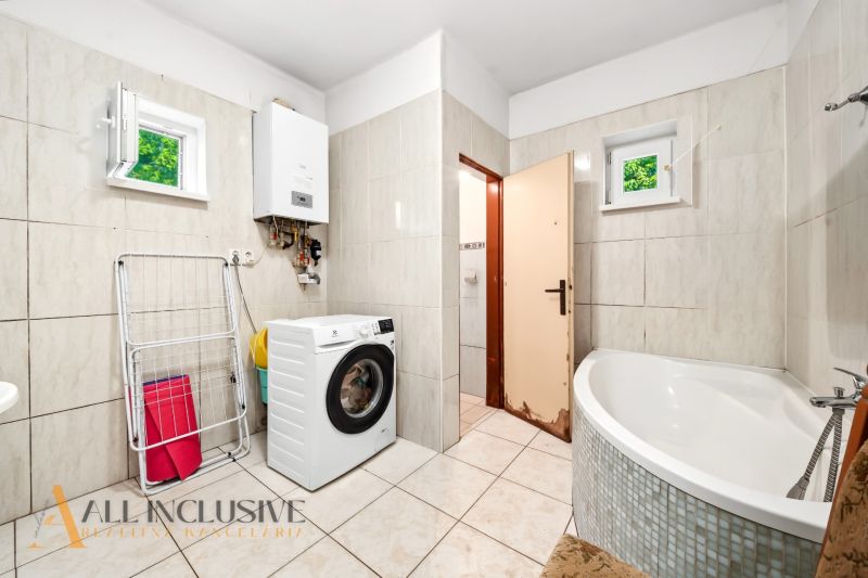 Badezimmer im Einfamilienhaus mit Waschmaschine, Eckbadewanne und Gasheizung.