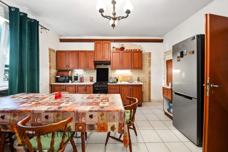 Küche in einem Einfamilienhaus mit Esstisch, Holzschränken und Kühlschrank.