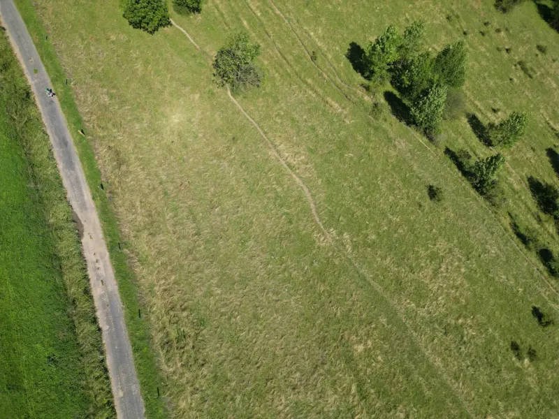 Luftaufnahme der Landschaft bei Stará Ľubovňa, die grüne Wiesen und eine Baumlandschaft hervorhebt.