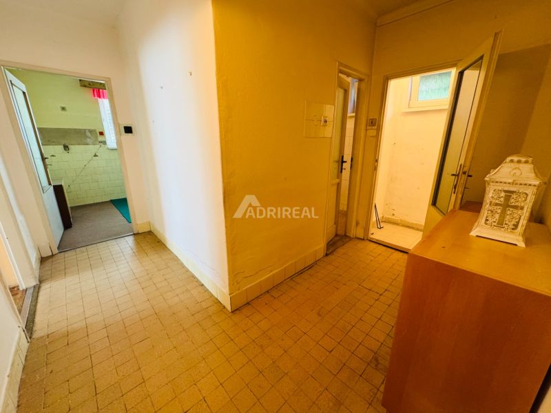 Der Flur einer 2-Zimmer-Wohnung mit Fliesen und mehreren offenen Türen.