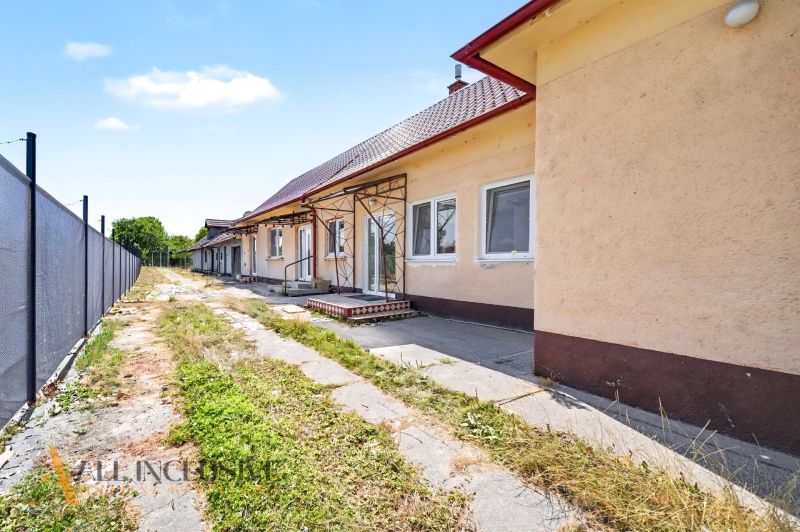 Ein Einfamilienhaus in Vydrany mit einer Veranda und einem Rasenstück, umgeben von einem Zaun.