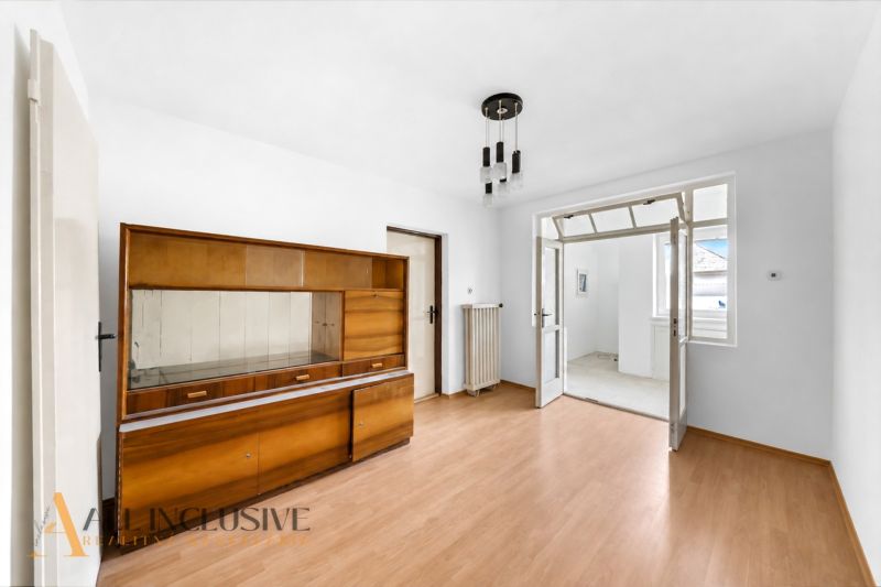 Ein Zimmer in einem Einfamilienhaus mit einem Holzboden und älteren Möbeln.