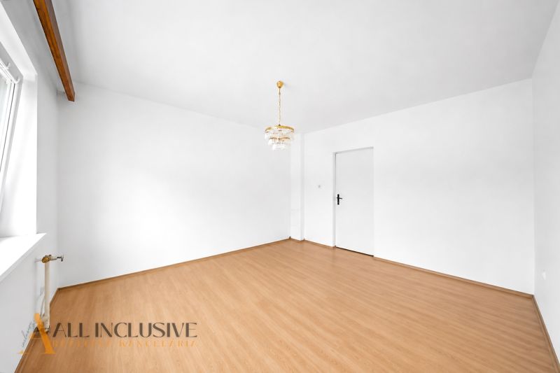 Weißes Zimmer in einem Einfamilienhaus mit Holzboden und Kronleuchter.
