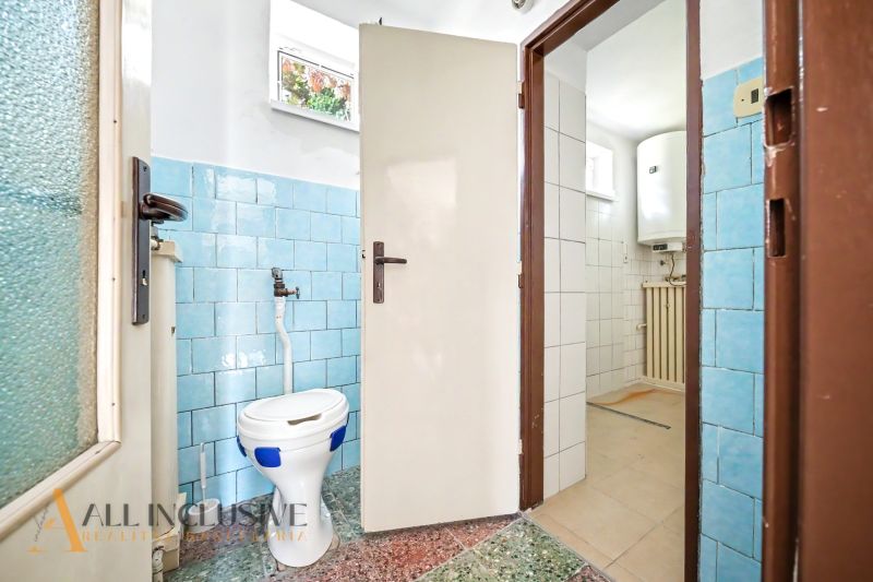 Ein Badezimmer in einem Einfamilienhaus mit blauen Fliesen und einer separaten Toilette.