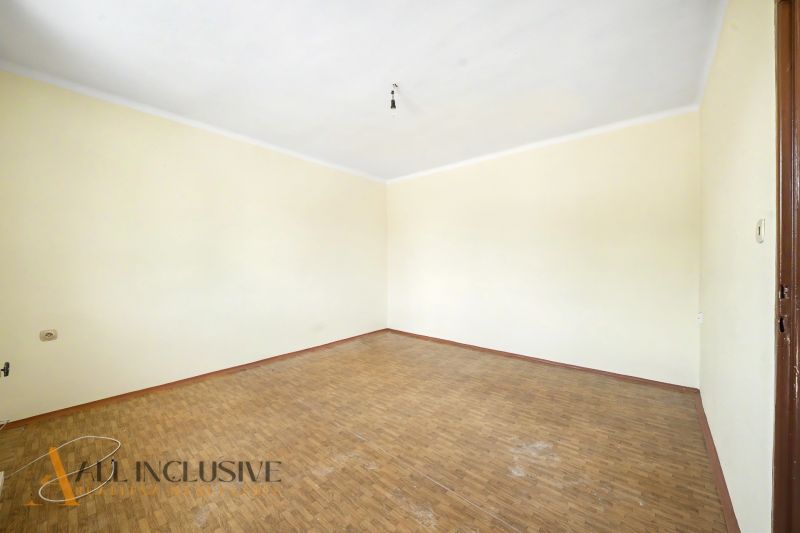Ein leerer Raum mit Holzboden und cremefarbenen Wänden in einem Einfamilienhaus.