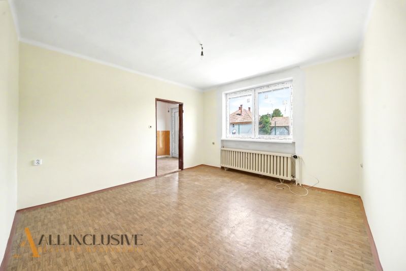 Geräumiger Raum mit Holzboden und großem Fenster in einem Einfamilienhaus.