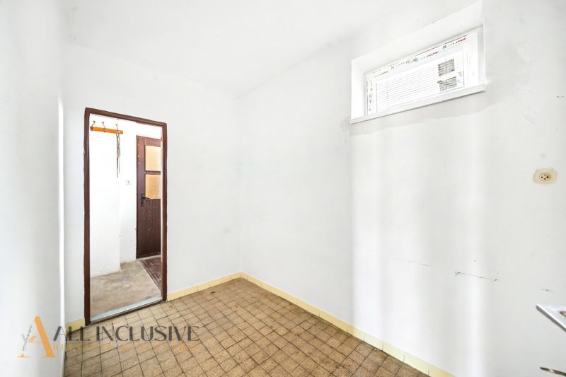 Ein Zimmer in einem Einfamilienhaus mit gefliestem Boden und weißen Wänden.