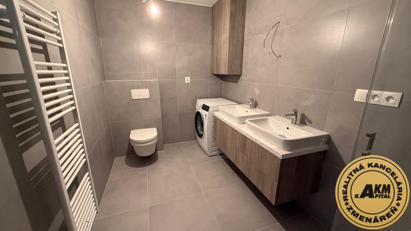 Badezimmer mit Doppelwaschbecken, Waschmaschine und Toilette in einer 3-Zimmer-Wohnung.