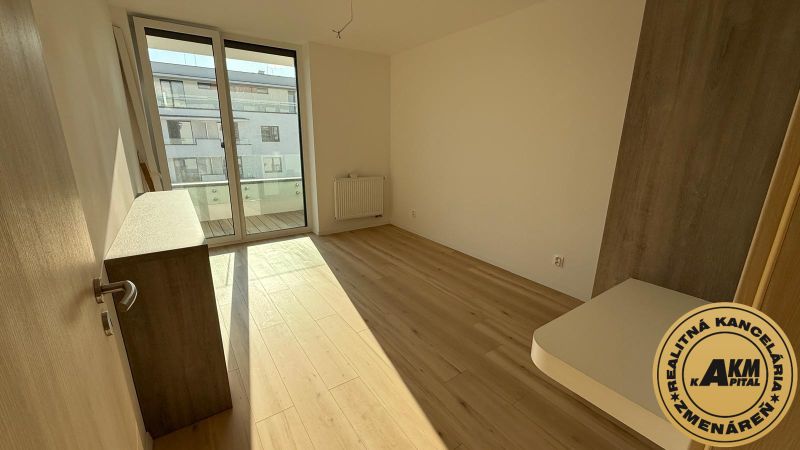 Ein Zimmer in einer 3-Zimmer-Wohnung mit einem Boden in Holzoptik und großen Fenstern.