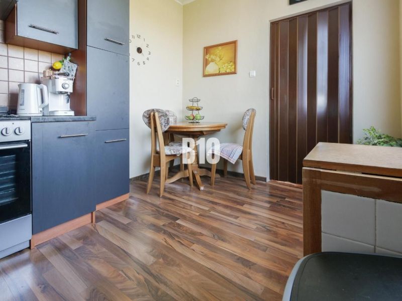 Küchenecke in einer 2-Zimmer-Wohnung mit Holzboden und Esstisch.