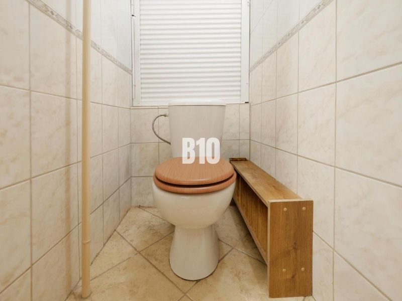 Badezimmer mit Toilette und Holzboden in einer 2-Zimmer-Wohnung.