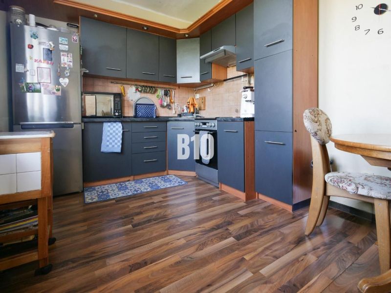 Küche in einer 2-Zimmer-Wohnung mit Holzboden und dunklen Möbeln.