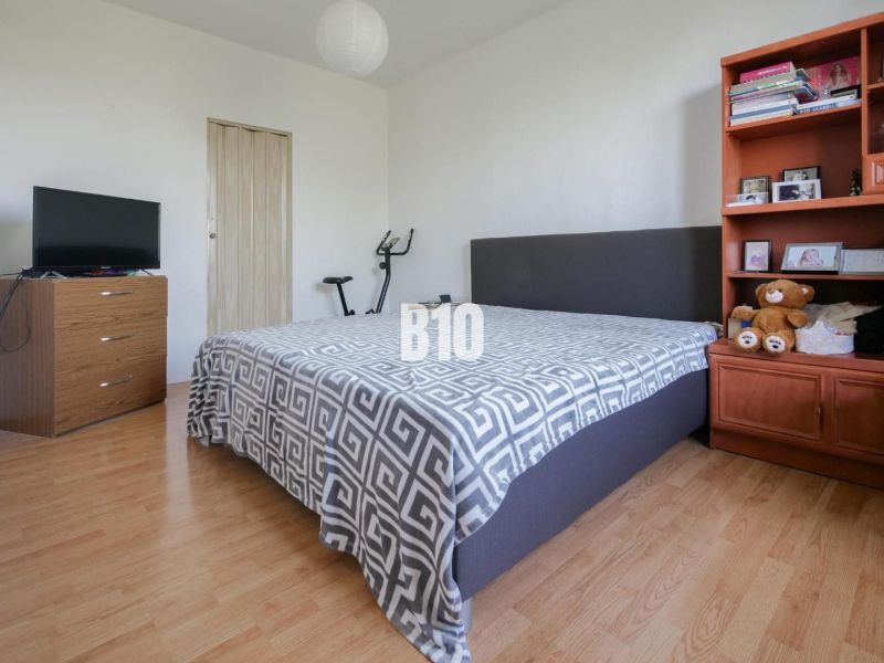 Schlafzimmer in einer 2-Zimmer-Wohnung mit Holzboden, Bett und Regal.
