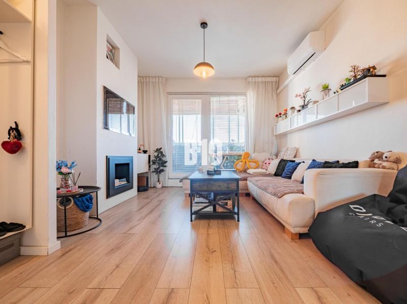 Wohnzimmer in einer 3-Zimmer-Wohnung mit Holzboden, Sofa und Kamin.