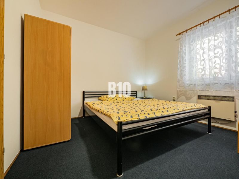 Schlafzimmer in einem Einfamilienhaus mit einem Metallbett, einem Schrank und gemusterten Vorhängen.