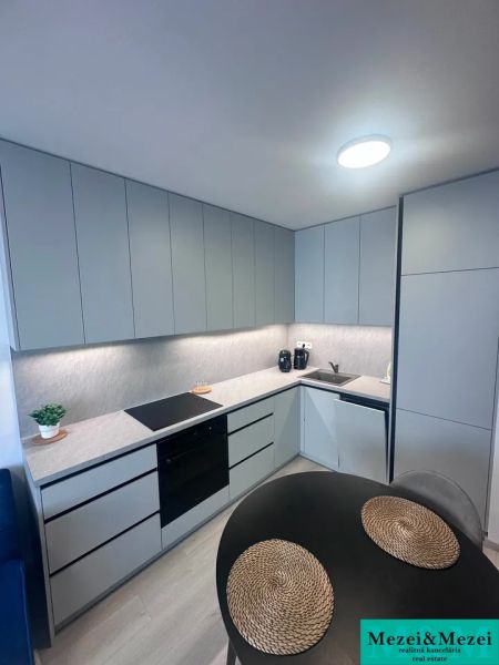 Küche in einer 2-Zimmer-Wohnung mit Holzboden und grauen Schränken.