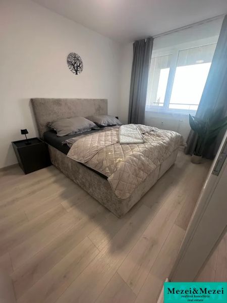 Schlafzimmer in einer 2-Zimmer-Wohnung mit einem Bett und einem Boden in Holzoptik.