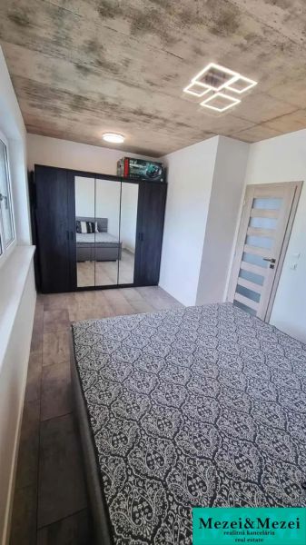 Schlafzimmer in einem Einfamilienhaus mit Holzboden, einem Spiegelschrank und einem Bett.