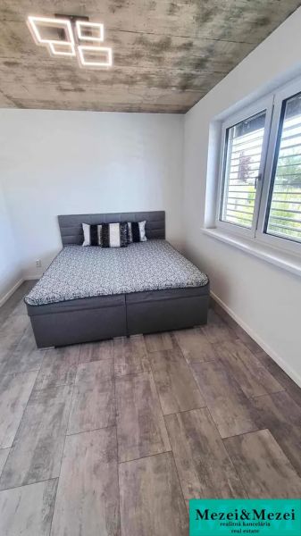 Schlafzimmer mit Bett, Fenster und Holzboden in einem Einfamilienhaus.