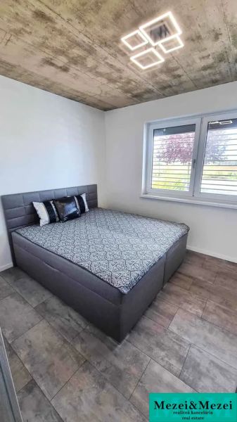 Einfamilienhaus mit einem Bett und einem Boden in Holzoptik, einfache Betondecke.