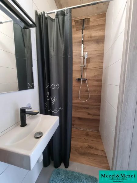 Badezimmer in einem Einfamilienhaus mit Holzdekor in der Duschkabine und Vorhang.