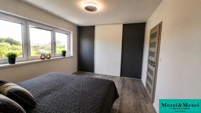 Schlafzimmer in einem Einfamilienhaus mit großem Fenster und Bett, Boden mit Holzdekor.