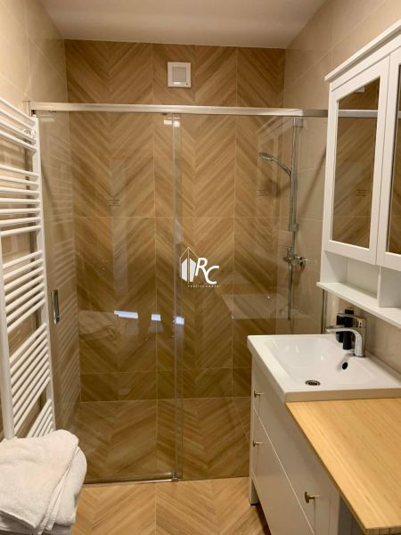 Badezimmer mit Duschkabine und Boden in Holzoptik in einer 3-Zimmer-Wohnung.