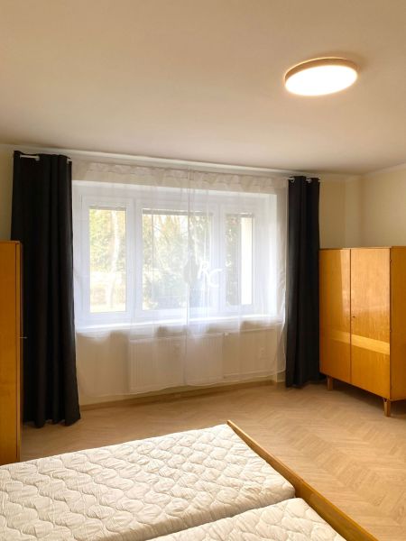 Helles Schlafzimmer mit großem Fenster und Holzboden in einer 3-Zimmer-Wohnung.