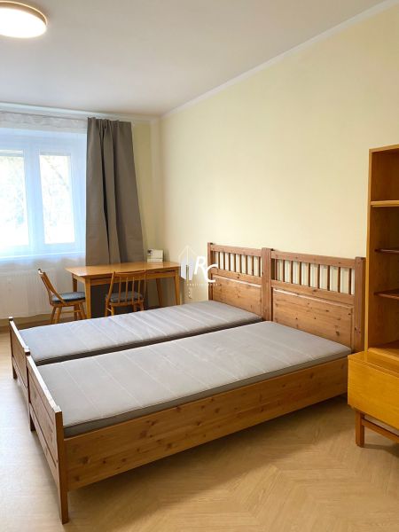 Schlafzimmer mit Holzbett, Tisch und Boden mit Holzdekor in einer 3-Zimmer-Wohnung.