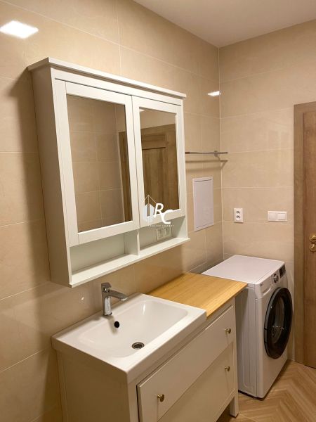 Badezimmer in einer 3-Zimmer-Wohnung mit Waschbecken, Spiegel und Waschmaschine, Keramikfliesen.