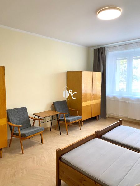 Ein Zimmer in einer 3-Zimmer-Wohnung mit einem Holzboden, zwei Sesseln und einem Schrank.