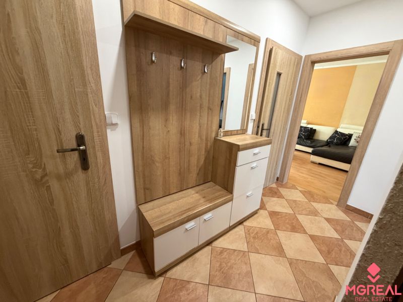 Eingangsbereich mit Spiegel und Schrank in einer 3-Zimmer-Wohnung. Boden mit Holzdekor.