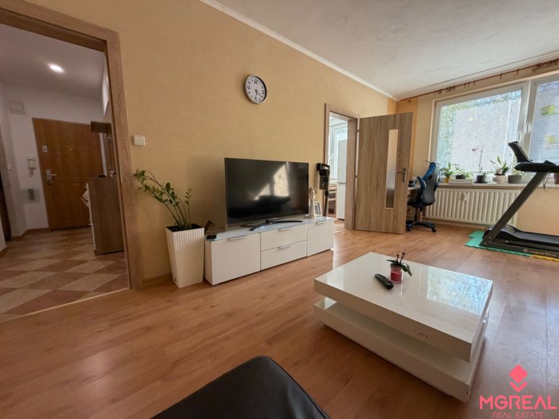Wohnzimmer in einer 3-Zimmer-Wohnung mit Holzboden, Fernseher und Laufband.