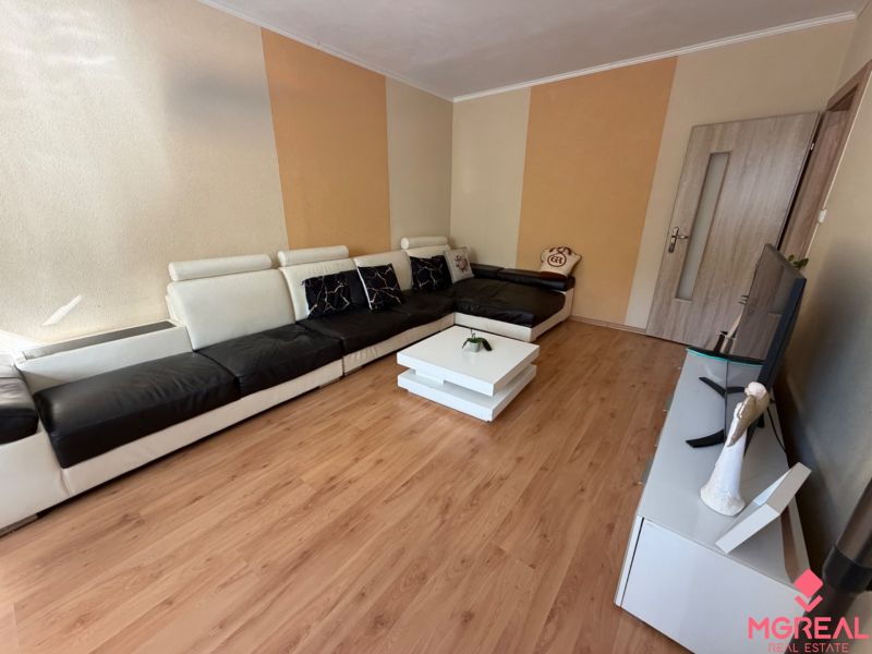 Wohnzimmer mit Sofa, Fernseher und Holzboden in einer 3-Zimmer-Wohnung.