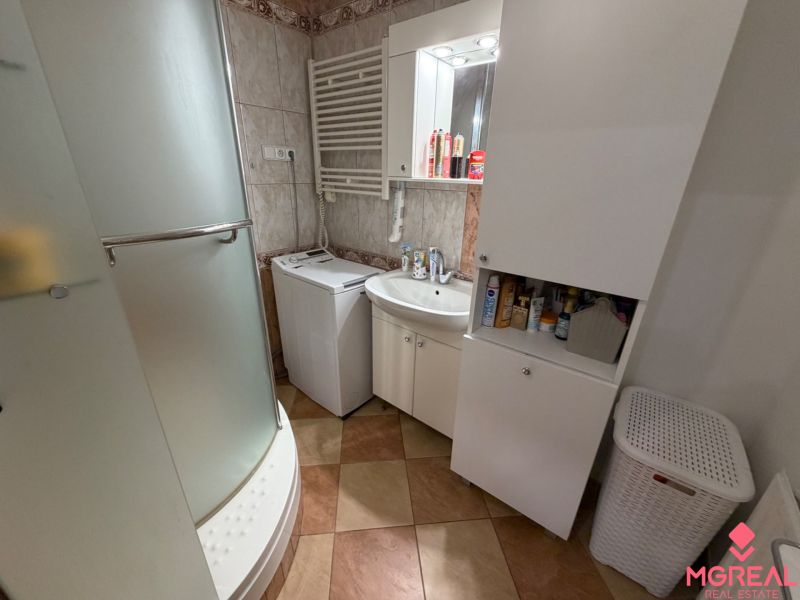 Badezimmer in einer 3-Zimmer-Wohnung mit Waschmaschine, Dusche und Aufbewahrungsschränken.