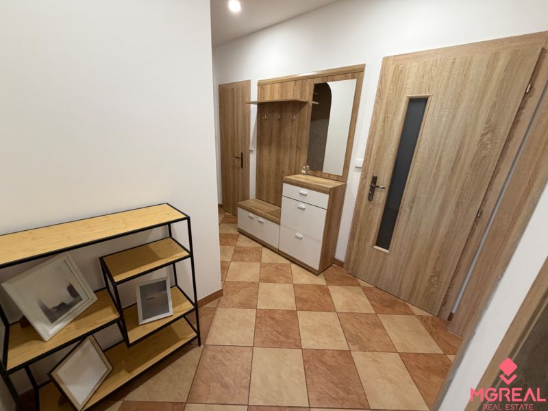 Flur in einer 3-Zimmer-Wohnung mit Fliesen, Garderobenwand und Regalen in Holzoptik.