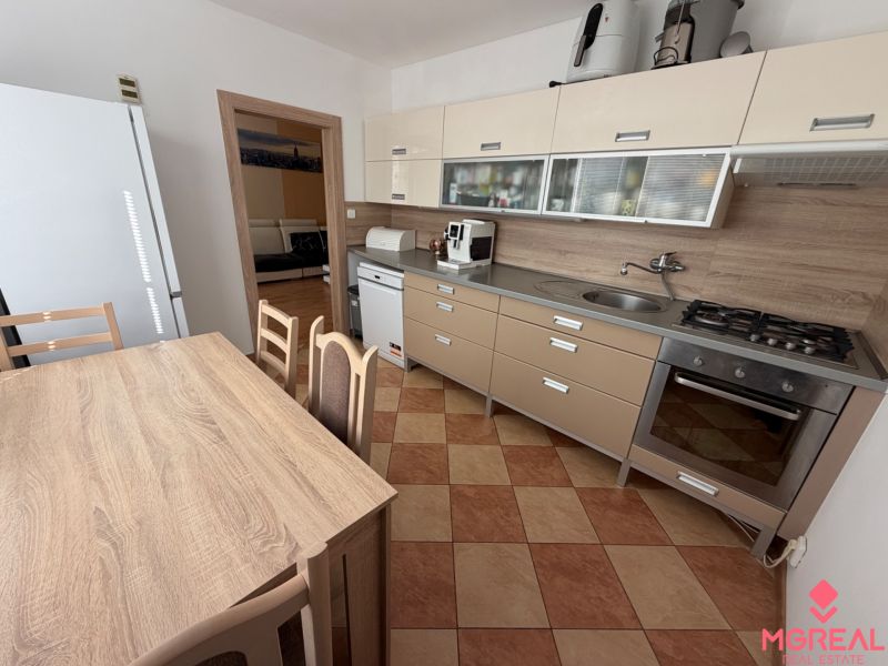 Küche einer 3-Zimmer-Wohnung mit Eckküche, Esstisch und Geräten.