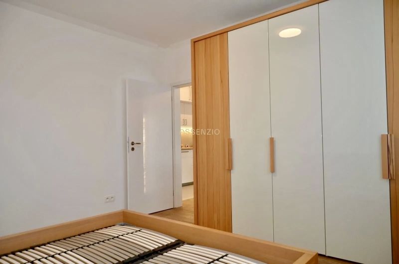 Schrank und Bettrahmen im Zimmer einer 3-Zimmer-Wohnung mit Holzboden.