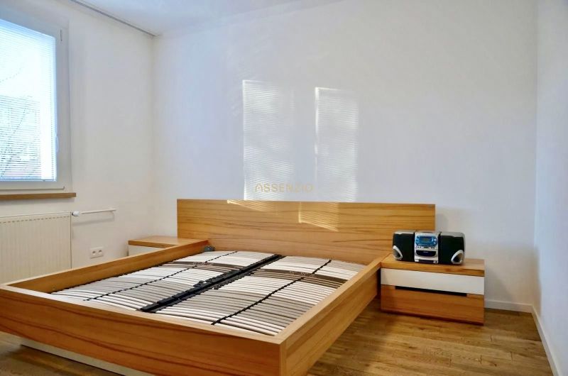 Schlafzimmer mit Bett und Nachttischen in einer 3-Zimmer-Wohnung, Boden mit Holzdekor.