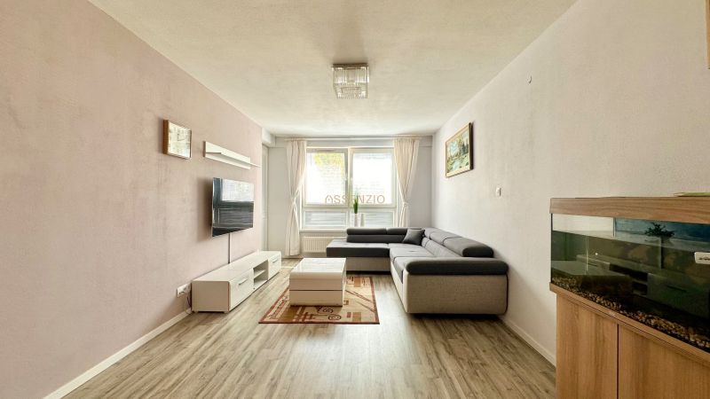 Wohnzimmer in einer 3-Zimmer-Wohnung mit Ecksofa und Boden in Holzoptik.