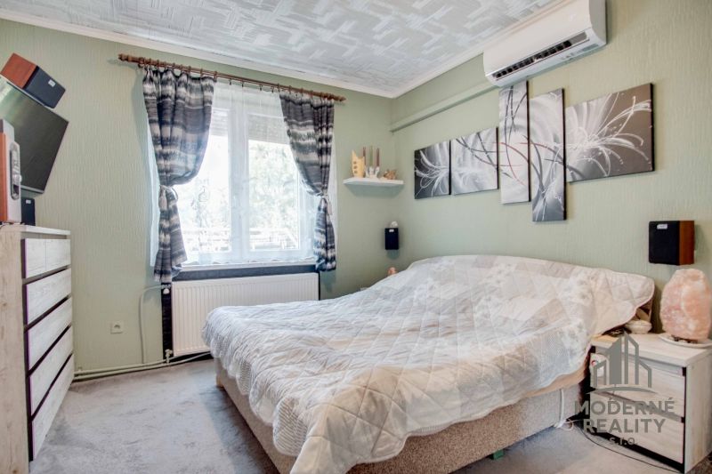 Schlafzimmer in einer 2-Zimmer-Wohnung mit Bett, Bildern und Klimaanlage an der Wand.
