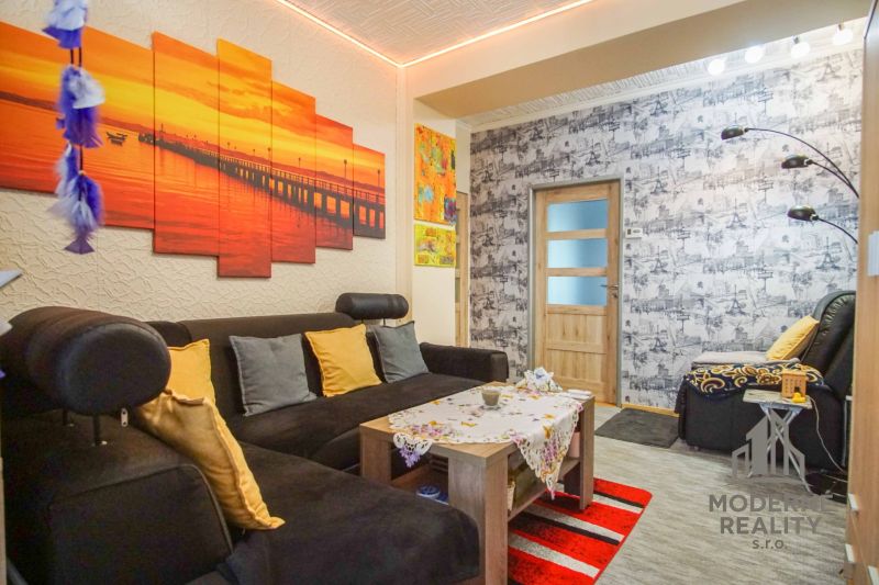 Wohnzimmer in einer Zweizimmerwohnung mit einem bequemen Sofa und bunten Dekorationen.