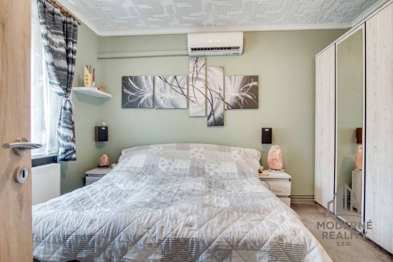 Schlafzimmer in einer 2-Zimmer-Wohnung mit Klimaanlage und abstrakten Bildern an der Wand.