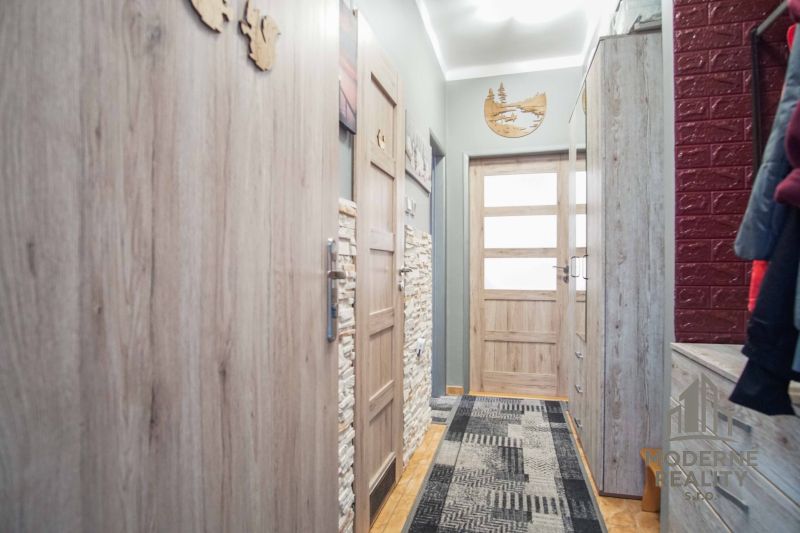 Ein schmaler Flur einer 2-Zimmer-Wohnung mit Holzelementen und Einrichtung.