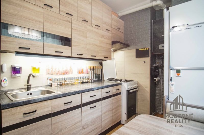 Küche in einer 2-Zimmer-Wohnung mit Holzboden und Geräten.